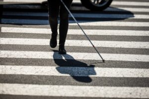 A blind person uses a cane to cross the street.