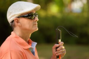 A blind man in a park with a cane.